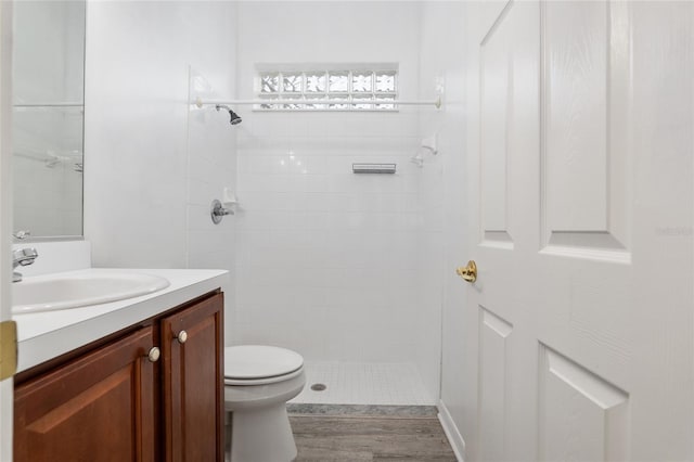 bathroom featuring tiled shower, wood-type flooring, vanity, and toilet