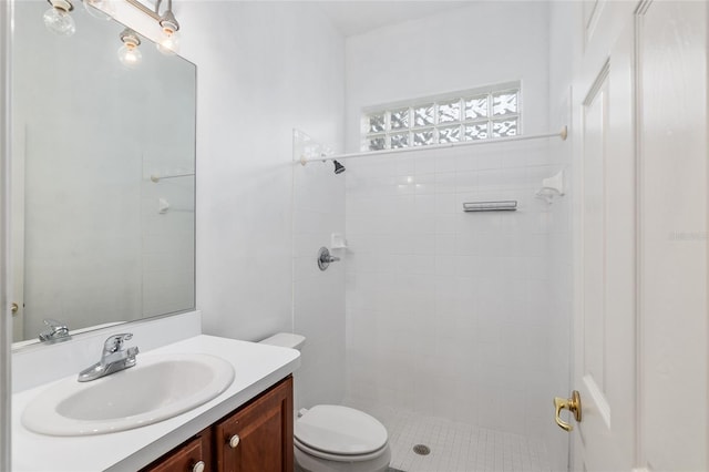 bathroom with a tile shower, tile patterned floors, vanity, and toilet