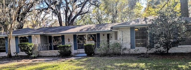 ranch-style house with brick siding, covered porch, and a front lawn