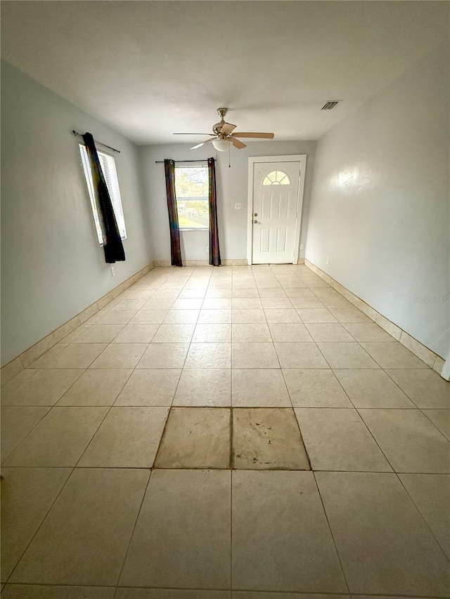 tiled spare room featuring ceiling fan