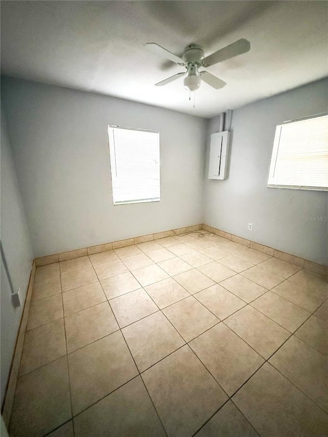 tiled empty room with electric panel and ceiling fan