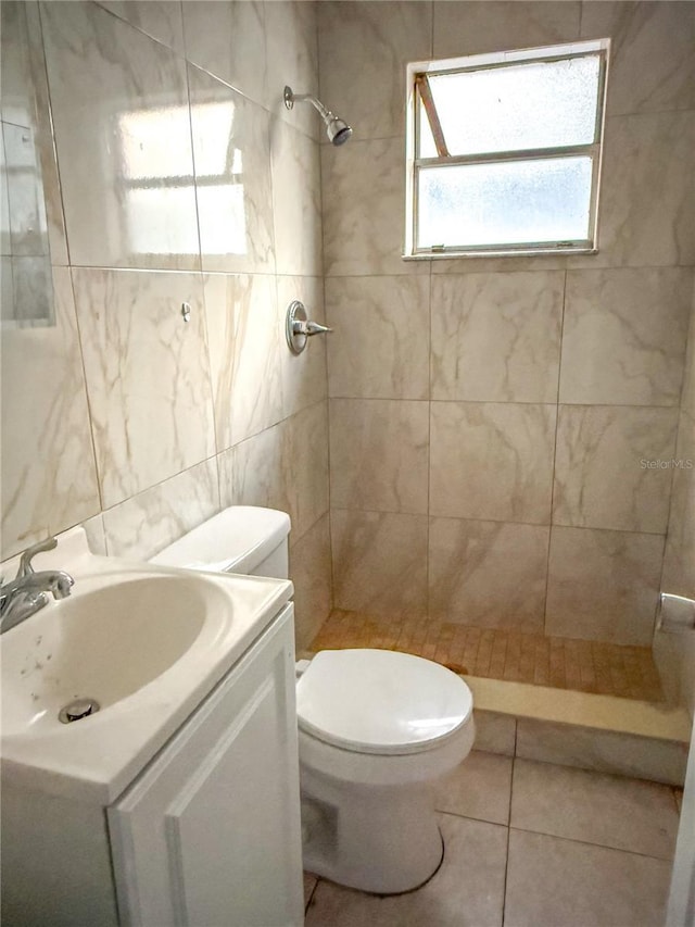 bathroom with tile patterned floors, toilet, a tile shower, and tile walls