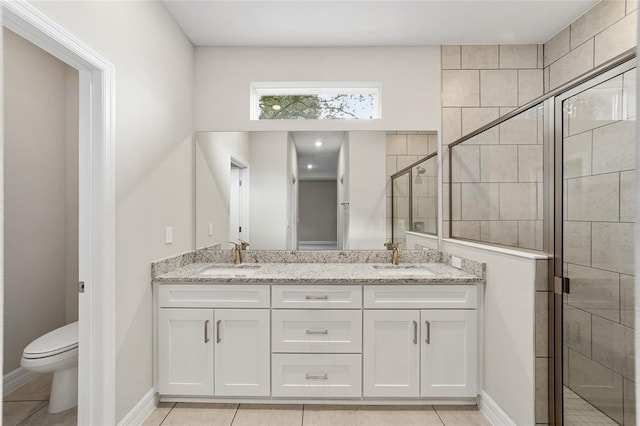 bathroom featuring tile patterned flooring, vanity, toilet, and a shower with door