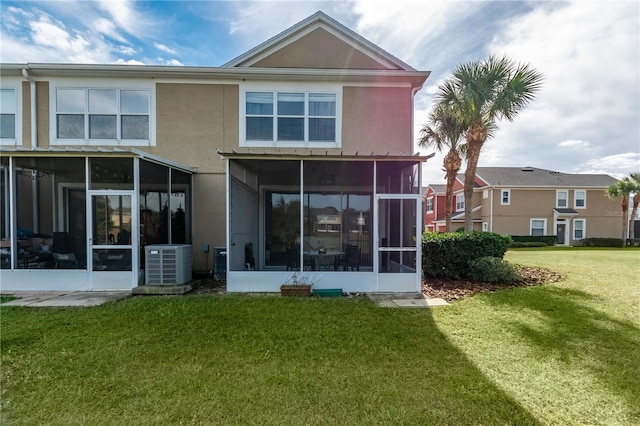 back of house with a lawn, a sunroom, and central AC