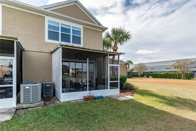 back of property featuring central AC unit, a yard, and a sunroom