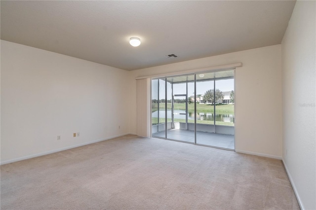 empty room featuring light carpet and a water view