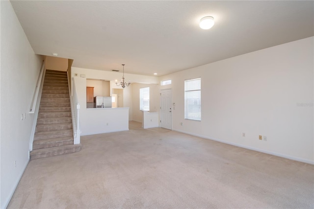 unfurnished living room with light carpet and a chandelier