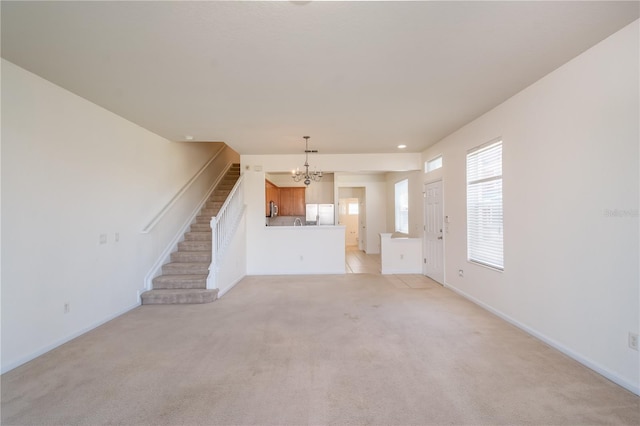 unfurnished living room featuring a notable chandelier and light carpet