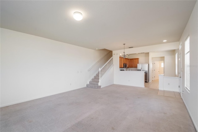 unfurnished living room featuring light carpet and a notable chandelier