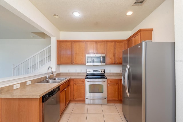 kitchen featuring light tile patterned floors, stainless steel appliances, a textured ceiling, and sink