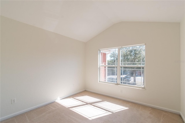 carpeted empty room featuring vaulted ceiling