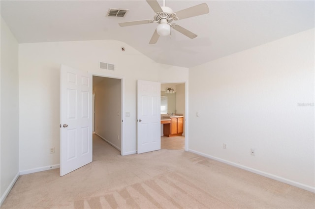 unfurnished bedroom featuring ceiling fan, vaulted ceiling, light colored carpet, and ensuite bathroom