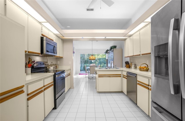 kitchen featuring kitchen peninsula, stainless steel appliances, sink, pendant lighting, and white cabinets