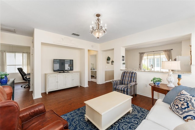 living room with dark hardwood / wood-style floors and an inviting chandelier