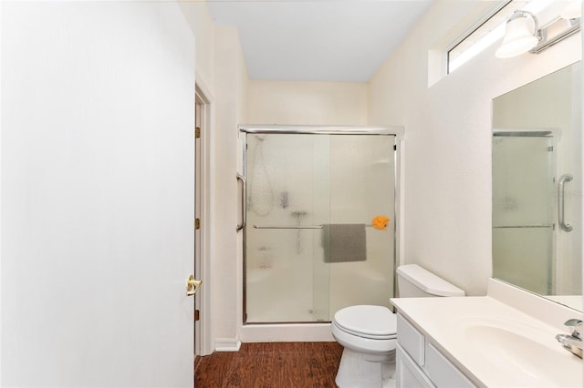 bathroom with wood-type flooring, vanity, toilet, and a shower with door