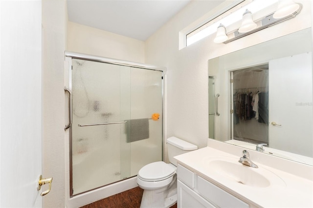 bathroom with hardwood / wood-style floors, vanity, toilet, and an enclosed shower