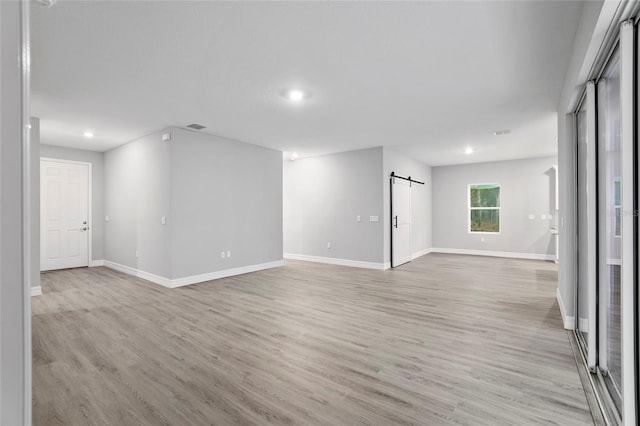 spare room featuring a barn door and light wood-type flooring