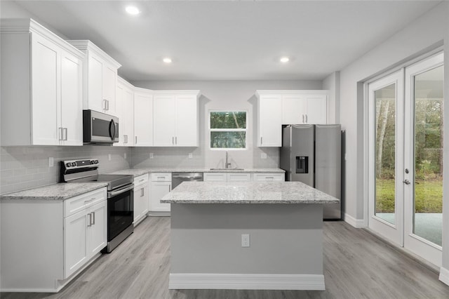 kitchen featuring a healthy amount of sunlight, a center island, white cabinetry, and stainless steel appliances