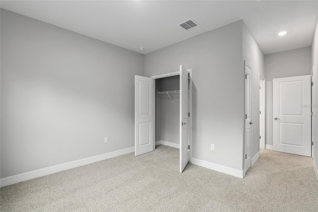 unfurnished bedroom featuring light carpet and a closet