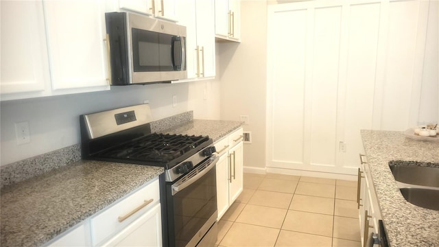 kitchen featuring white cabinetry, light tile patterned flooring, light stone counters, and appliances with stainless steel finishes