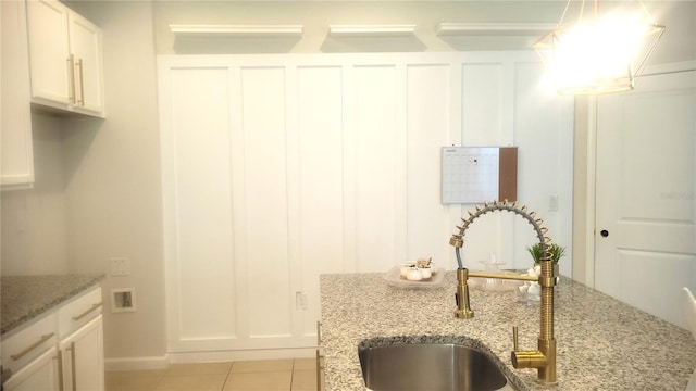 kitchen featuring white cabinets, light stone counters, and sink