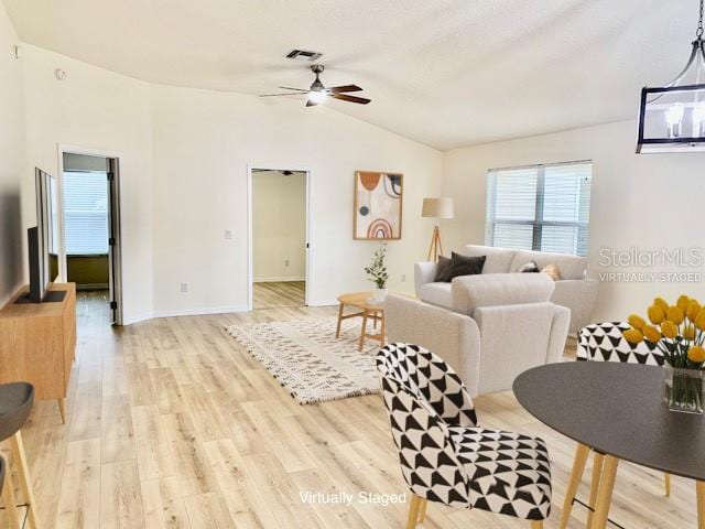 living room featuring ceiling fan, light hardwood / wood-style flooring, and vaulted ceiling