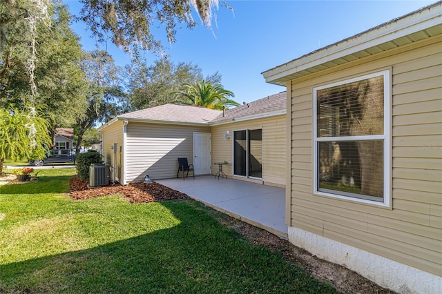 rear view of property with central AC unit, a patio area, and a lawn