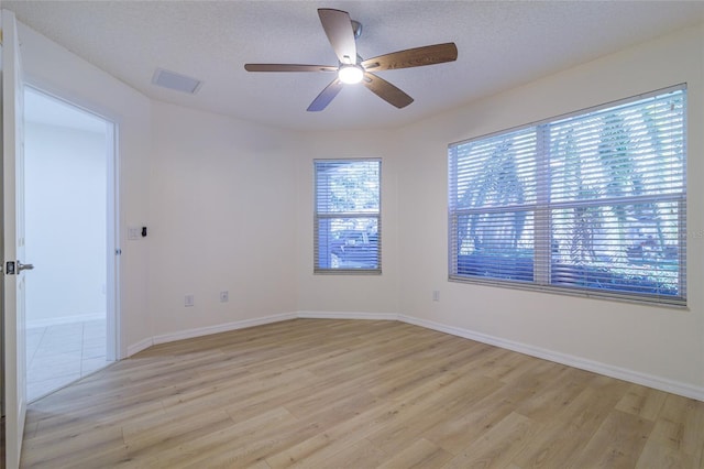 spare room with ceiling fan, light hardwood / wood-style flooring, and a textured ceiling