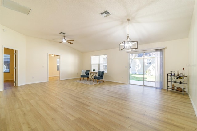 unfurnished living room with lofted ceiling, light hardwood / wood-style flooring, and ceiling fan with notable chandelier