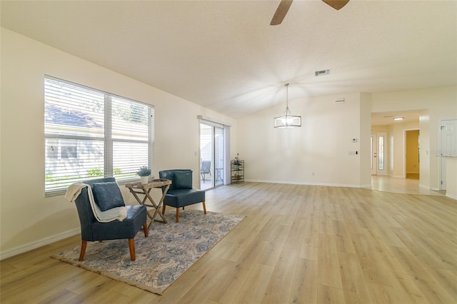 sitting room featuring light hardwood / wood-style flooring, ceiling fan with notable chandelier, and lofted ceiling