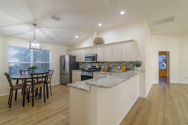 kitchen with kitchen peninsula, appliances with stainless steel finishes, light wood-type flooring, light stone counters, and decorative light fixtures