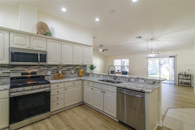 kitchen with kitchen peninsula, sink, light hardwood / wood-style floors, and appliances with stainless steel finishes