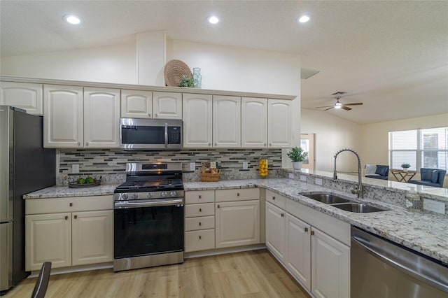 kitchen with decorative backsplash, stainless steel appliances, ceiling fan, sink, and lofted ceiling