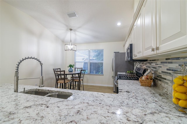 kitchen featuring tasteful backsplash, light stone counters, stainless steel appliances, sink, and white cabinetry