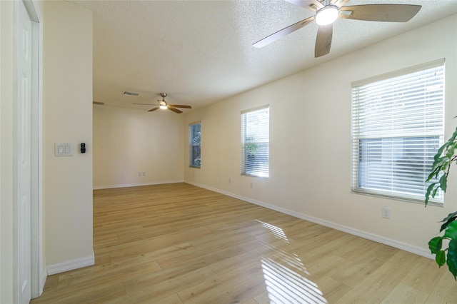 empty room with a healthy amount of sunlight, a textured ceiling, and light wood-type flooring