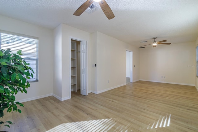 unfurnished living room with ceiling fan, a textured ceiling, and light wood-type flooring