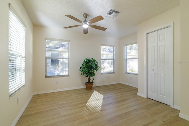 spare room with a textured ceiling, light hardwood / wood-style floors, and ceiling fan