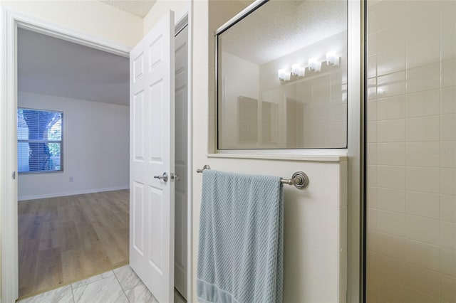 bathroom with hardwood / wood-style floors, an enclosed shower, and a textured ceiling