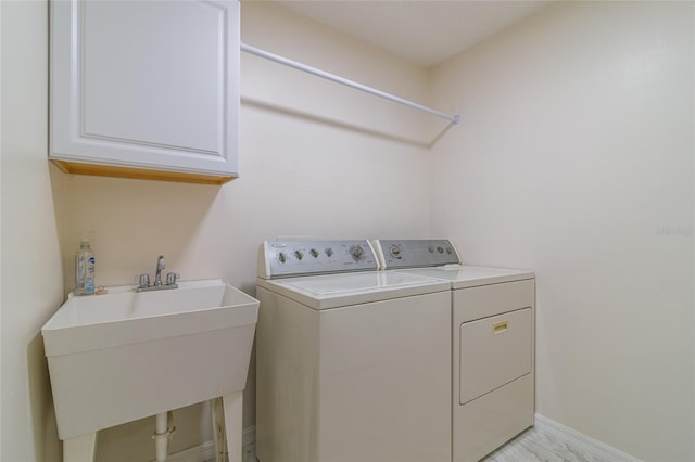 laundry room with cabinets, independent washer and dryer, and sink