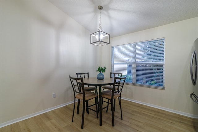 dining space with a textured ceiling, light hardwood / wood-style flooring, and a notable chandelier