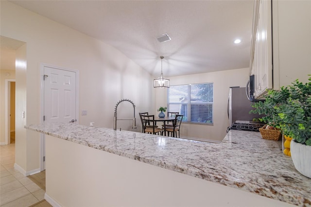 kitchen featuring an inviting chandelier, white cabinets, vaulted ceiling, decorative light fixtures, and light stone counters