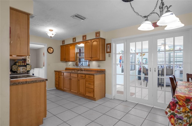 kitchen featuring light tile patterned floors, sink, decorative light fixtures, and washing machine and clothes dryer