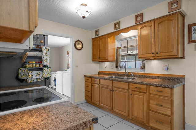 kitchen with washing machine and dryer, sink, light tile patterned floors, and a textured ceiling