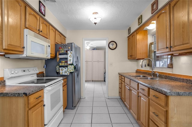 kitchen with ceiling fan, sink, a textured ceiling, white appliances, and light tile patterned floors