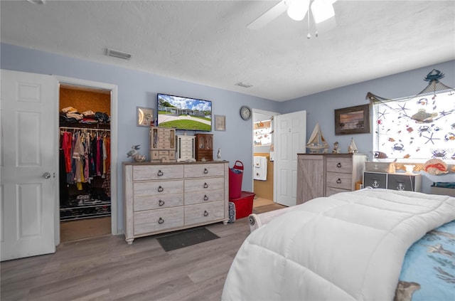 bedroom with ceiling fan, light wood-type flooring, a spacious closet, and a closet