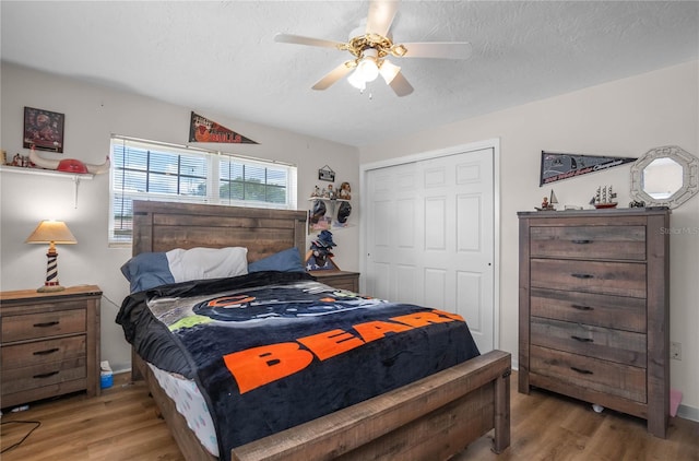 bedroom featuring hardwood / wood-style floors, a textured ceiling, a closet, and ceiling fan