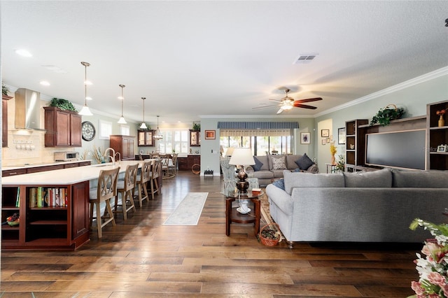 living room featuring dark hardwood / wood-style floors, ceiling fan, and crown molding