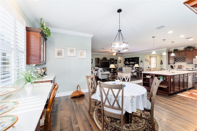 dining space with ceiling fan, sink, dark wood-type flooring, and ornamental molding