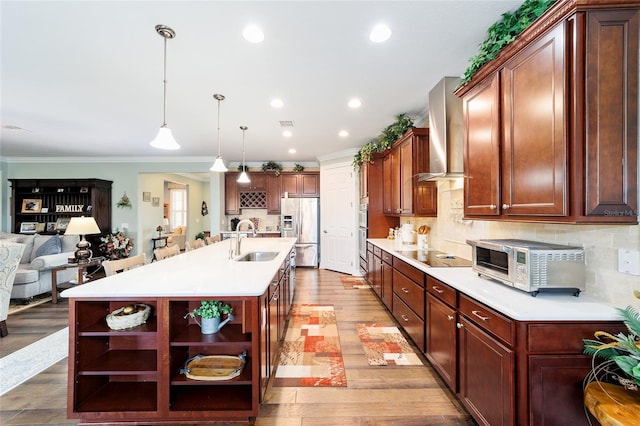 kitchen with light hardwood / wood-style floors, sink, an island with sink, and appliances with stainless steel finishes