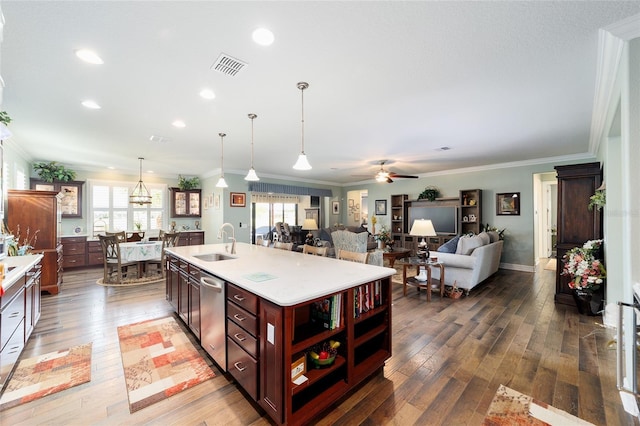 kitchen with wood-type flooring, a kitchen island with sink, ornamental molding, and sink